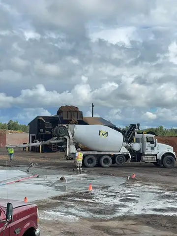 Concrete mixer unloading material at a construction site with workers